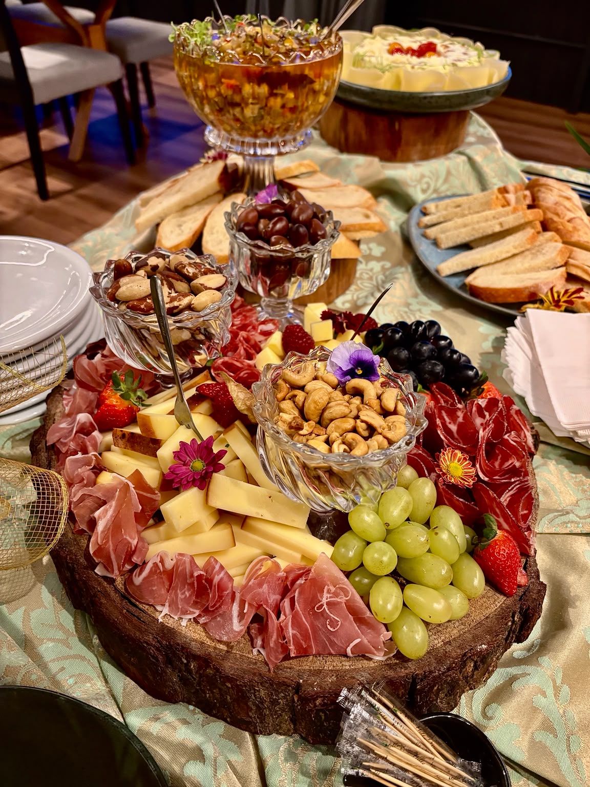 Mesa de frios com queijos, presuntos, frutas, castanhas e acompanhamentos