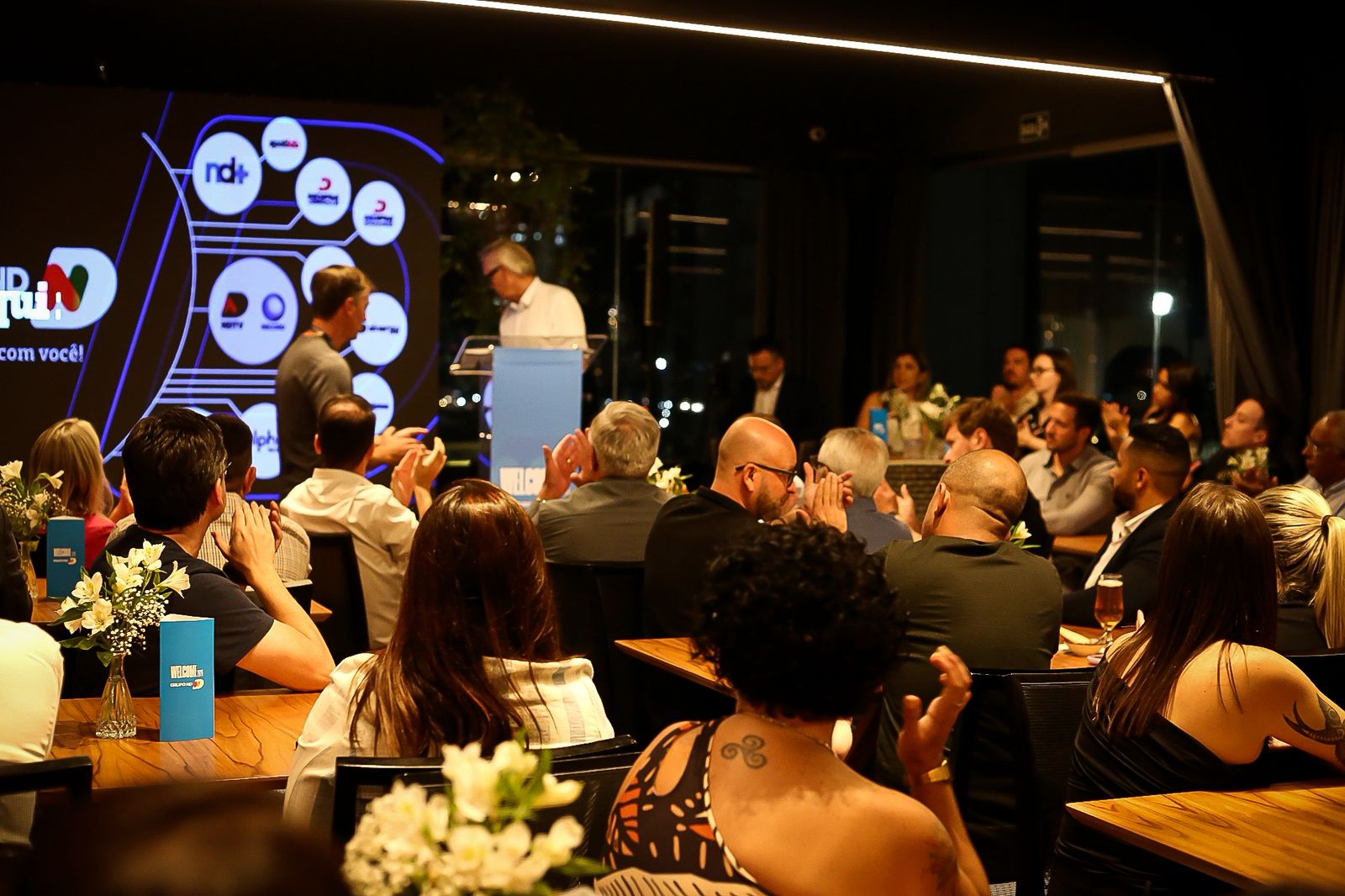 Convidados aplaudindo durante apresentação em evento corporativo