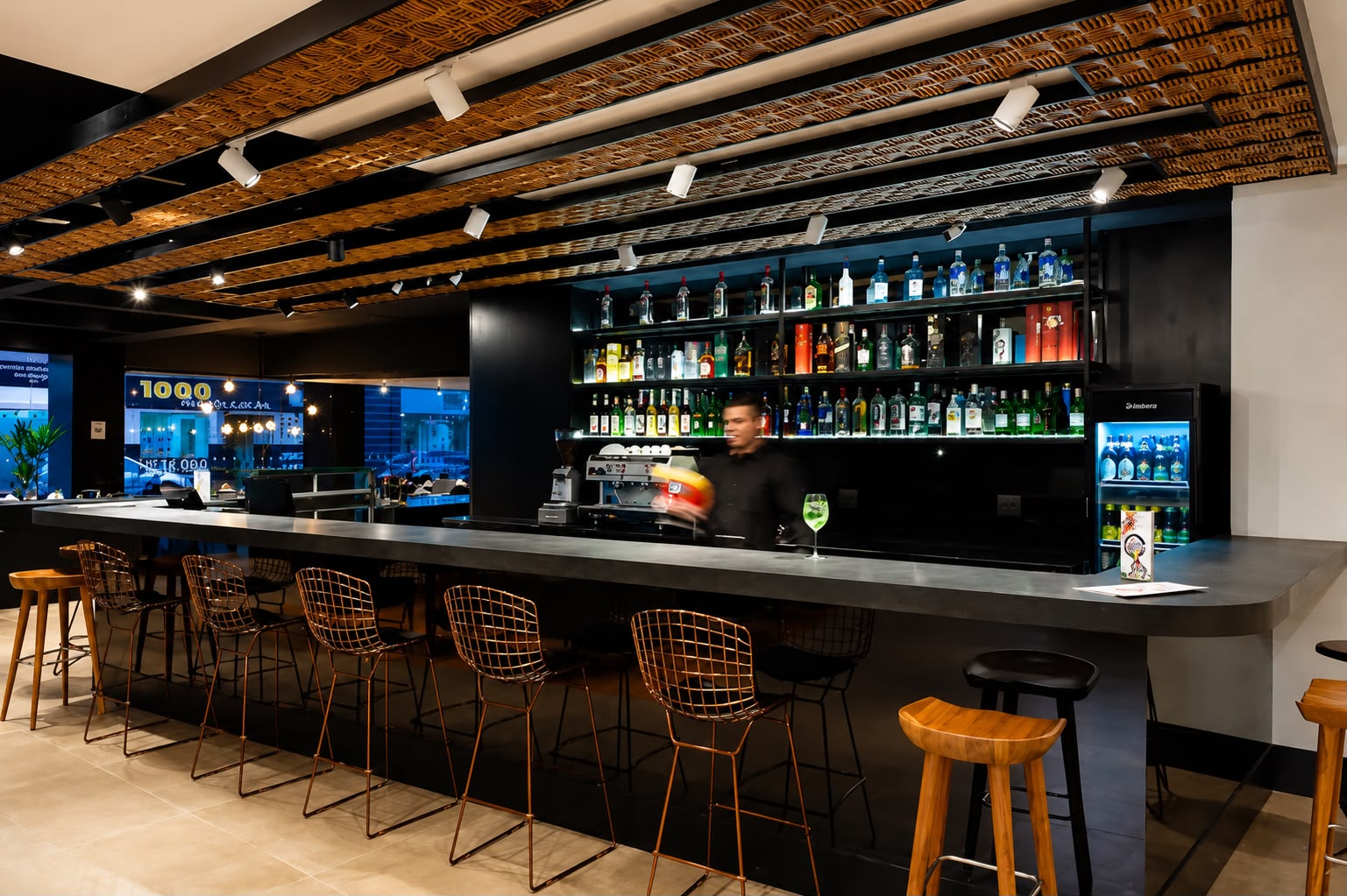 Bar do The Sailor com bartender e prateleiras iluminadas