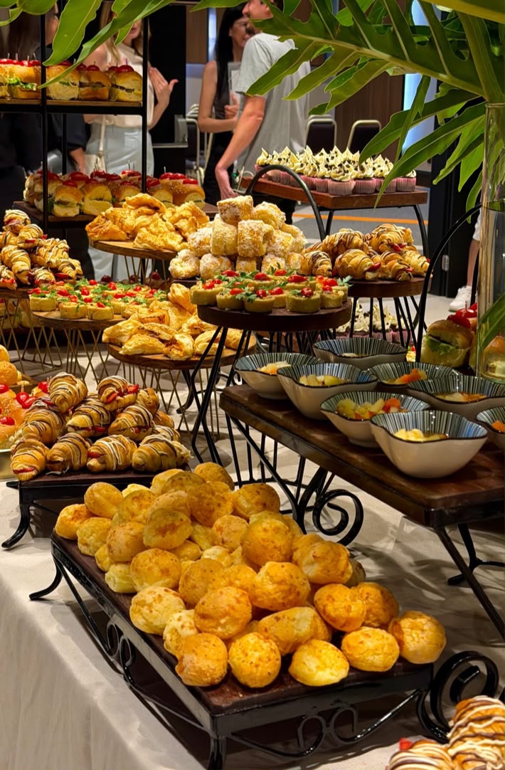 Mesa de coffee break com salgados, mini pães e arranjo verde