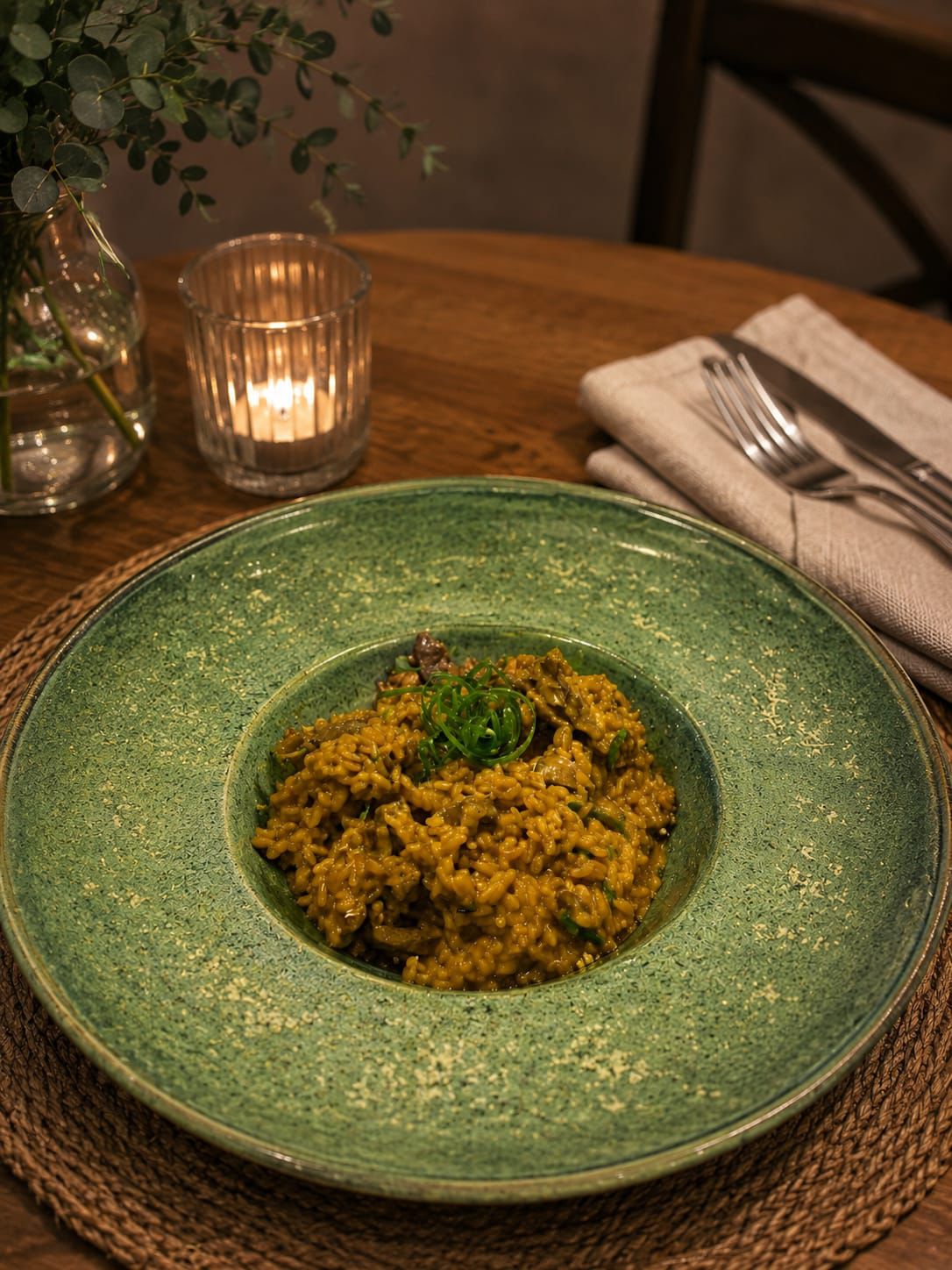 Risoto servido em prato verde à luz de velas
