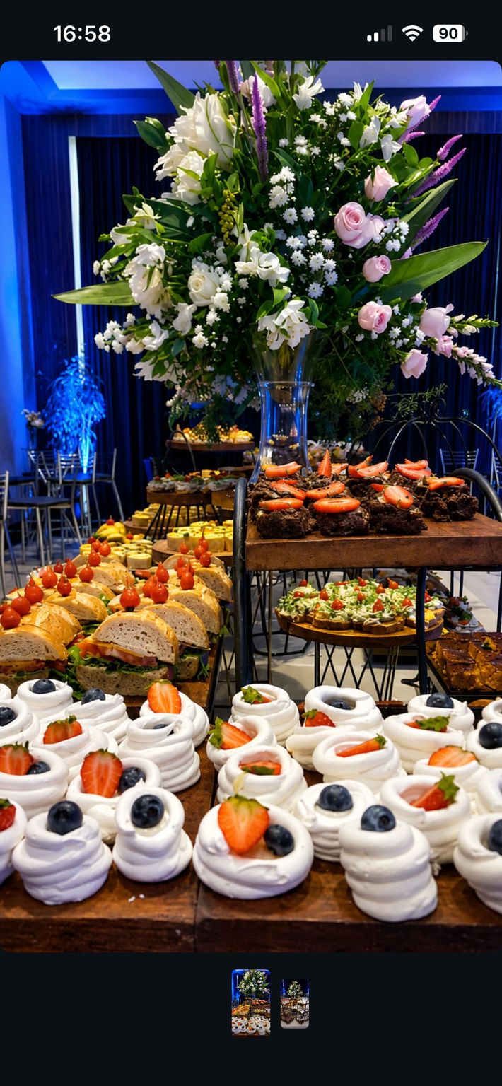 Mesa de doces e salgados com arranjo floral em evento noturno