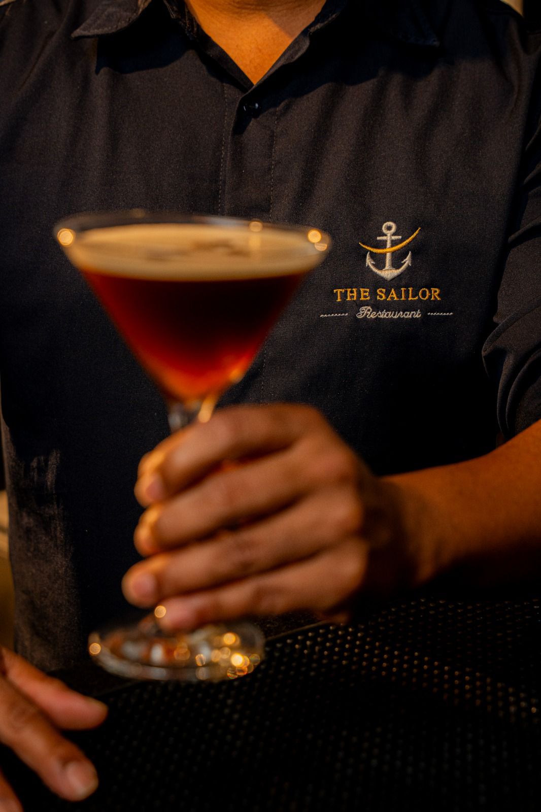 Drink autoral do The Sailor servido em taça de cristal com twist de laranja