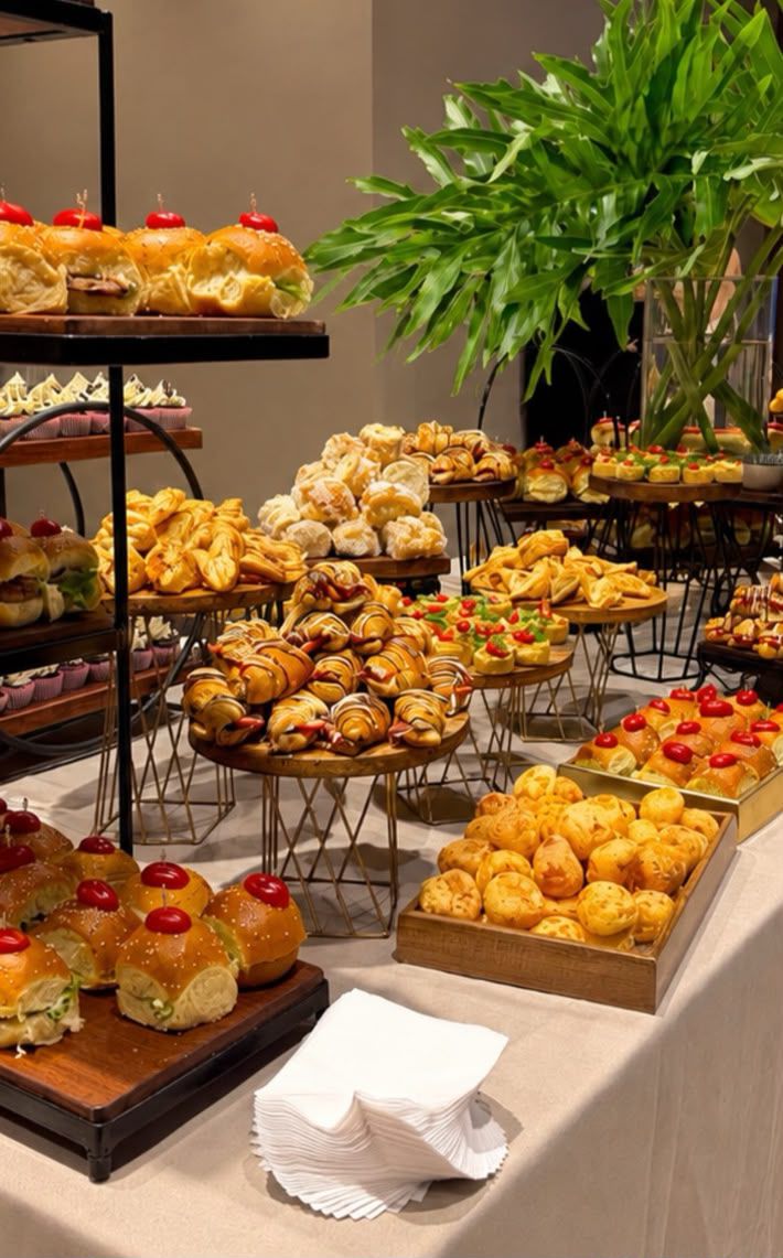Mesa de coffee break com pães, salgados e doces em bandejas
