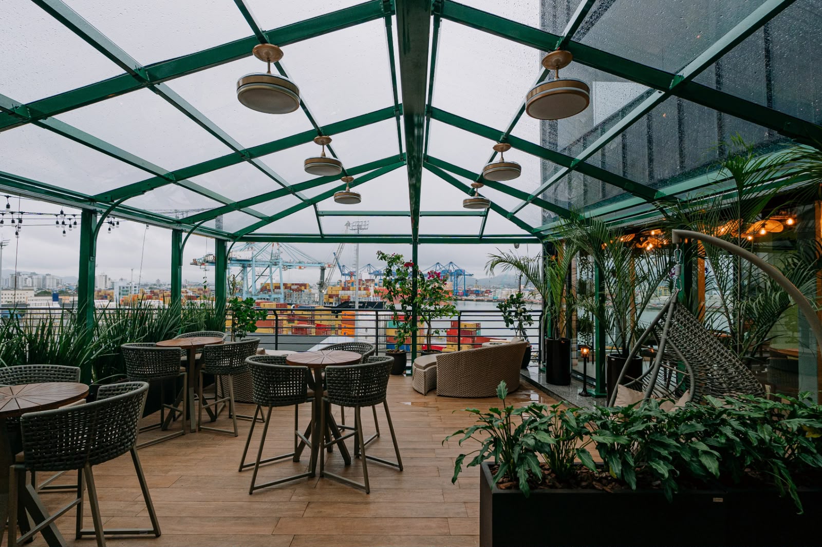 Varanda envidraçada com estrutura verde e vista para o porto